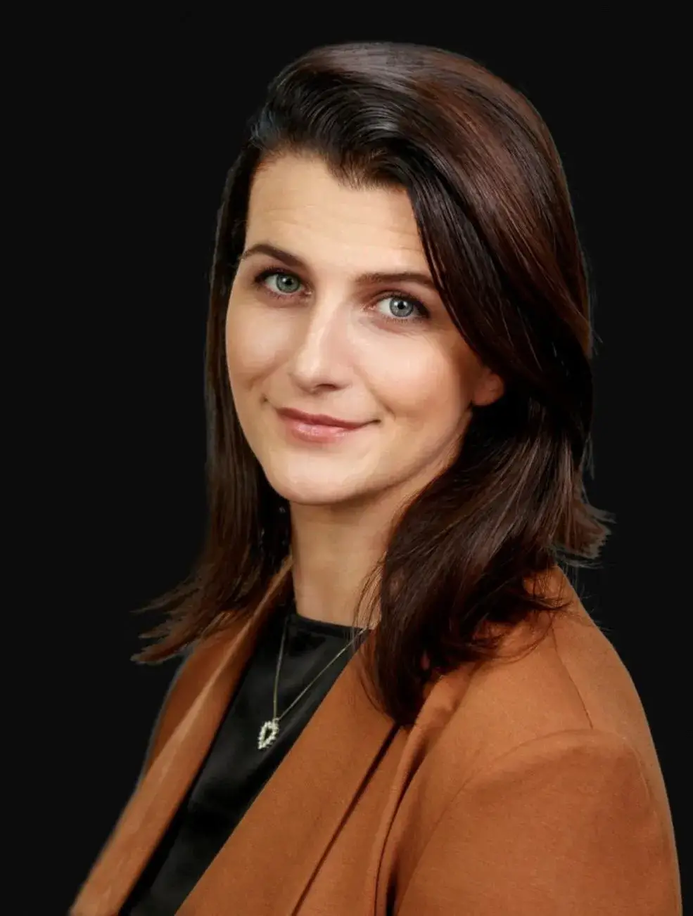 Laura Winkel, chief executive officer, in a portrait with dark hair, wearing a tan jacket against a black background