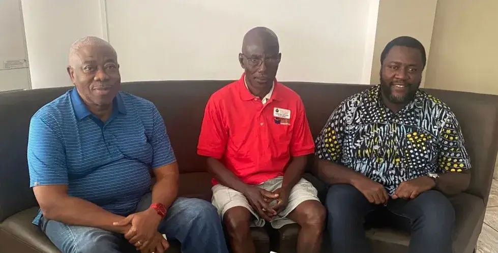 Three men seated side by side on a sofa: Samuel Thompson on the left in a blue shirt, Steve Arthur in the centre in a red shirt, and Geoffrey Lartey on the right in a patterned shirt
