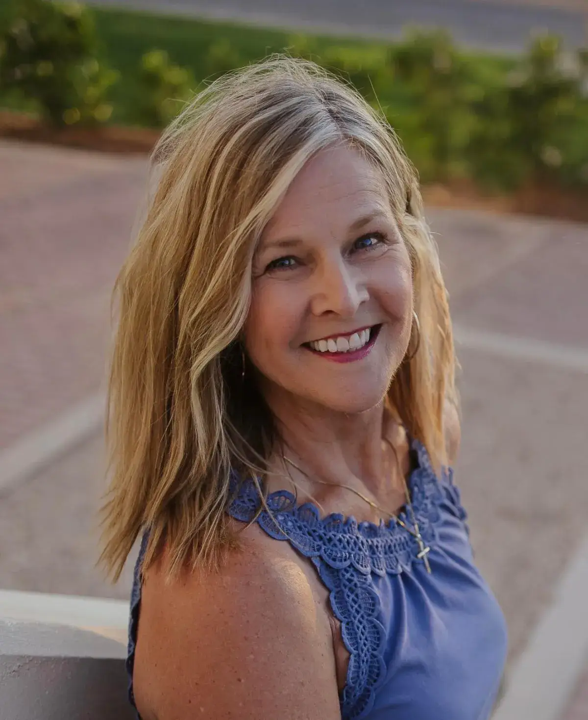 Donna Wyland, the author, smiling, with long fair hair and a blue sleeveless top, in a portrait