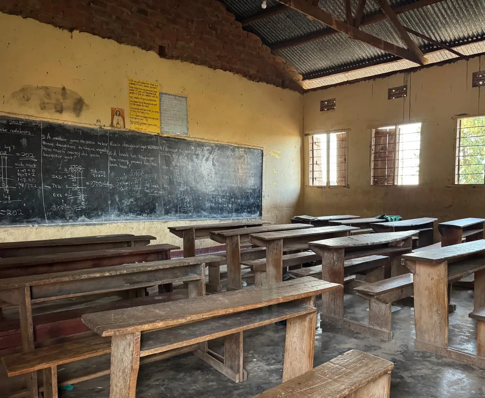 A long classroom with a chalk-covered blackboard and wooden desks
