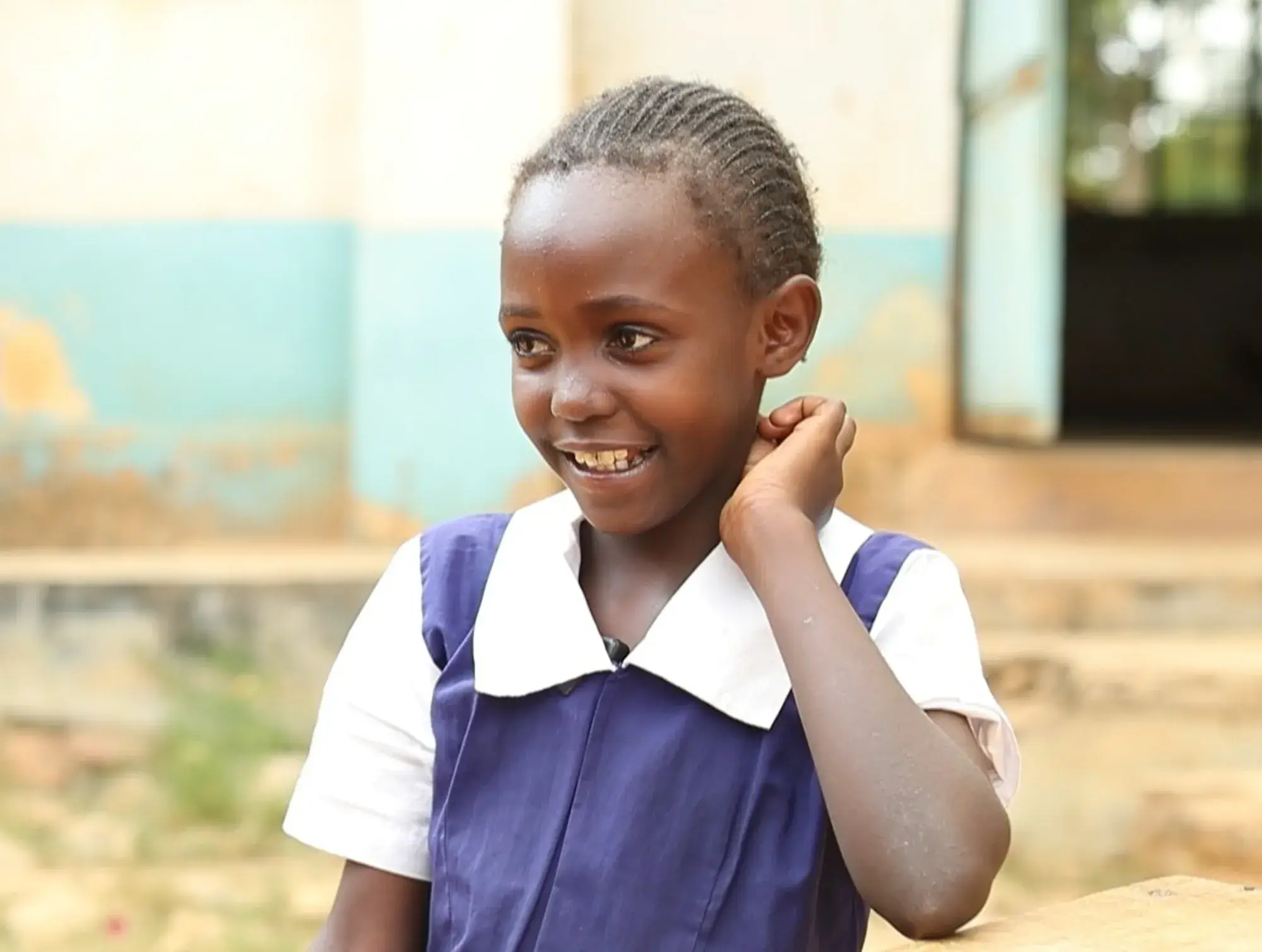 A smiling schoolgirl in a blue and white uniform