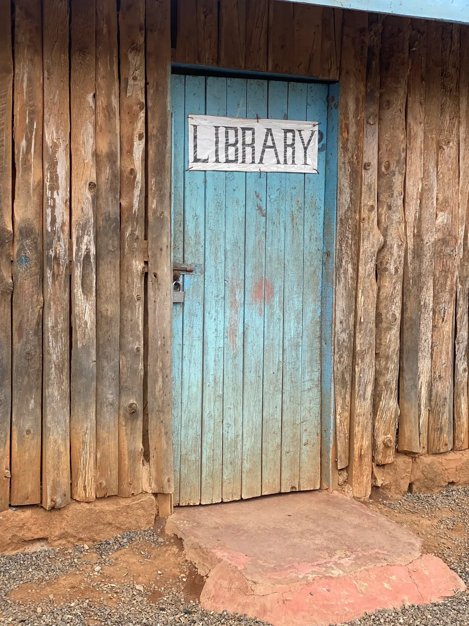 A blue door marked LIBRARY in a wall of rough timber planks