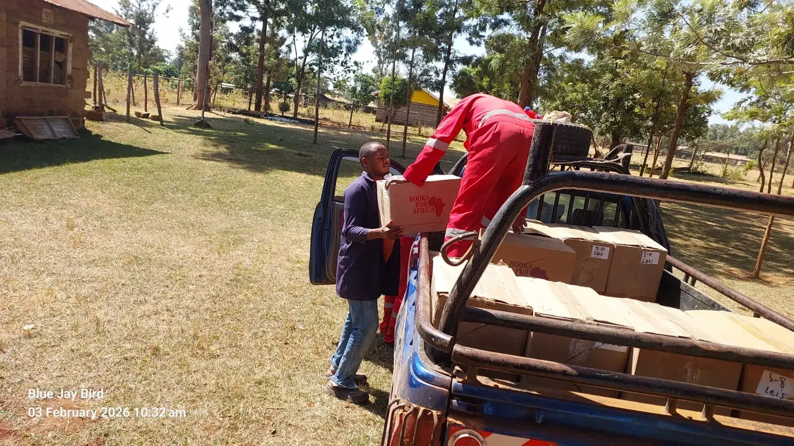 Two people unloading book boxes from a pickup truck