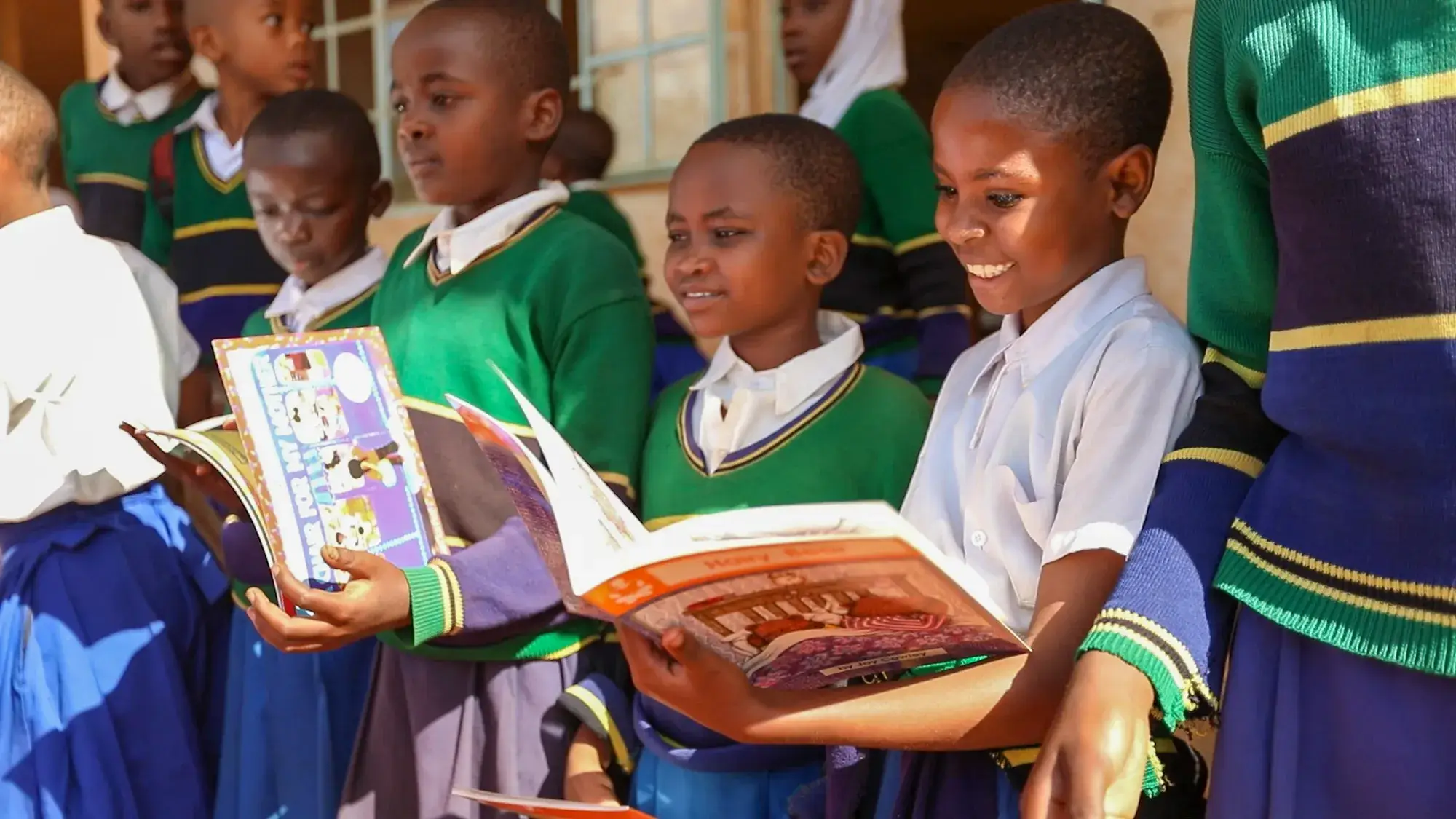 Pupils in school uniforms smiling over open picture books