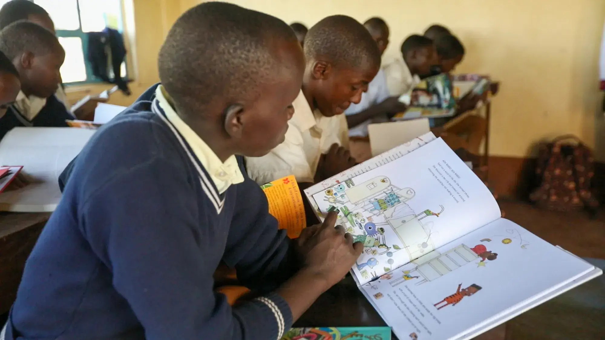 Students at their desks reading illustrated books