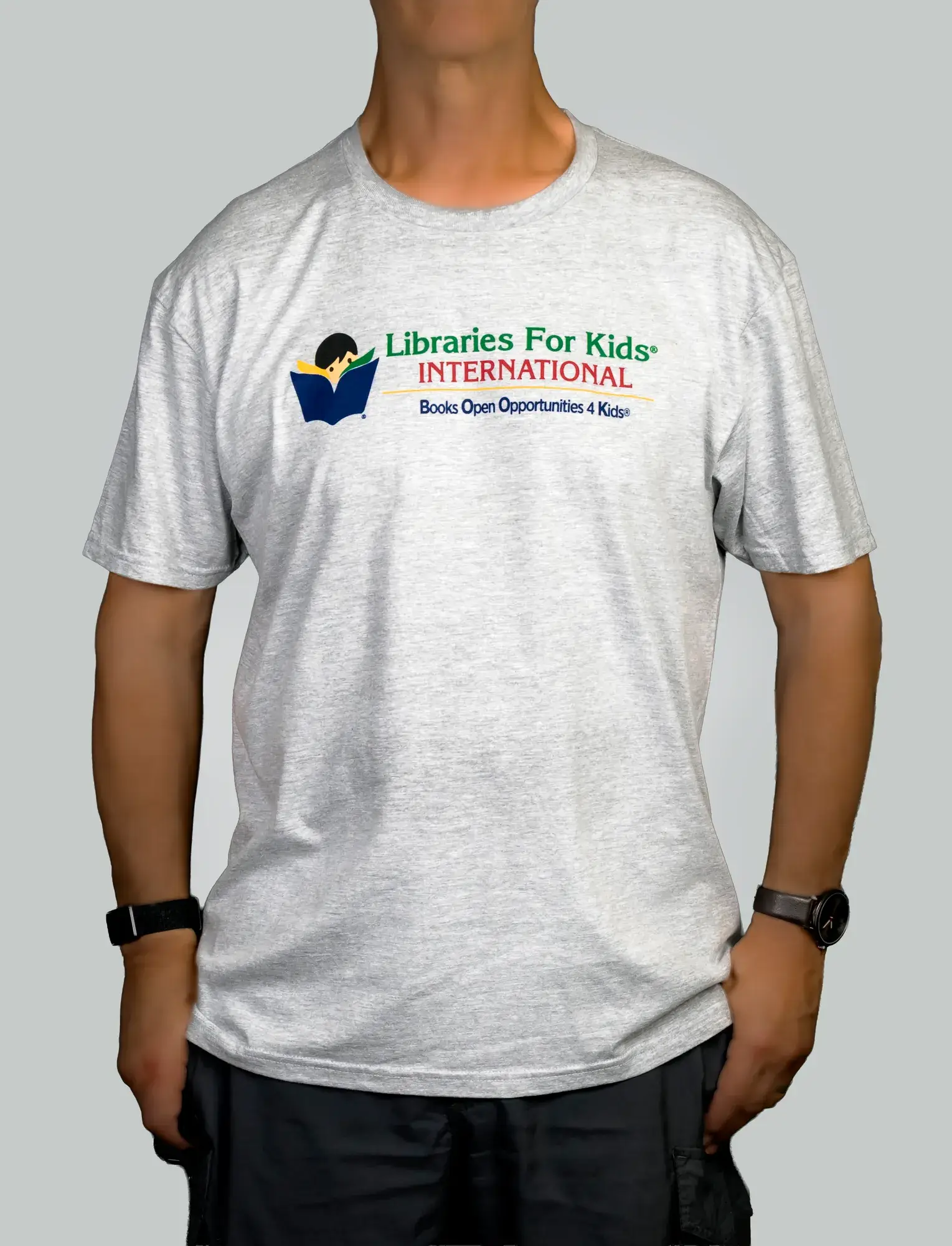A person wearing the grey T-shirt, front view, with the Libraries For Kids International logo on the chest